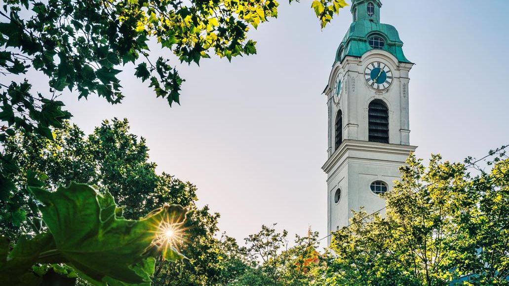 Kirch Sankt Heinrich in der Südstadt umringt von Bäumen bei abendlichem Sonnenschein.
