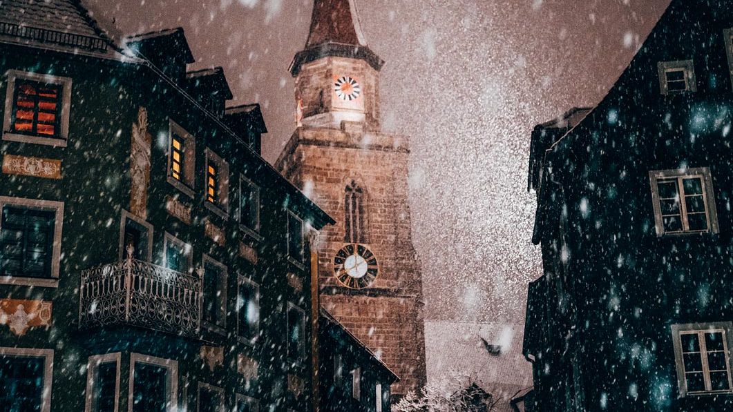 Blick auf den Kirchturm Sankt Michael bei nächtlichem Schneefall.