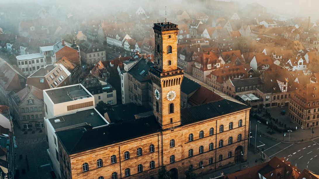 Blick von oben auf das Rathaus bei Nebel. Im Hintergrund die Altstadt und der Kirchturm von Sankt Michael.