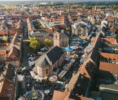 View over the Michaelis Kirchweih Fair Fairground rides and booths along the Königstrasse during the Michaelis Kirchweih Fair. In the fore is the church